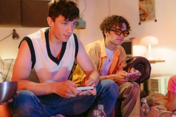 teenage boys sitting on brown couch playing video game console